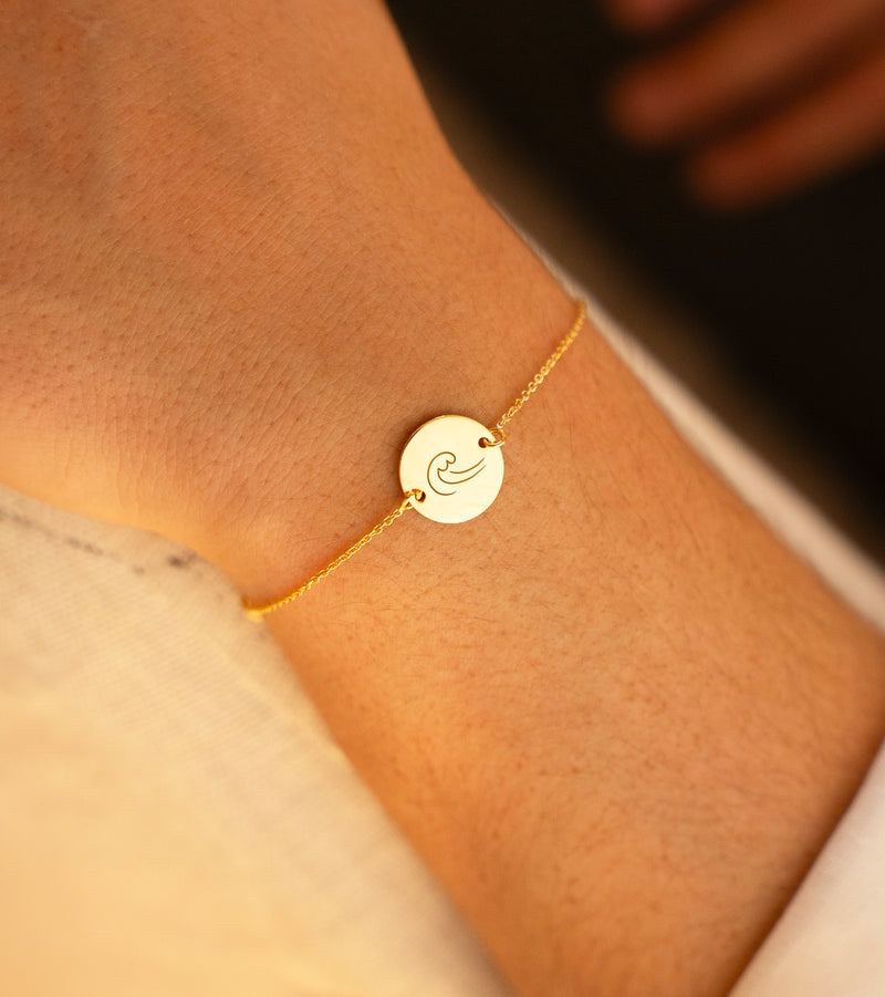 Bracelet en plaqué or, agrémenté d'une médaille de 15mm dotée de deux trous, suspendue à une chaîne maille.