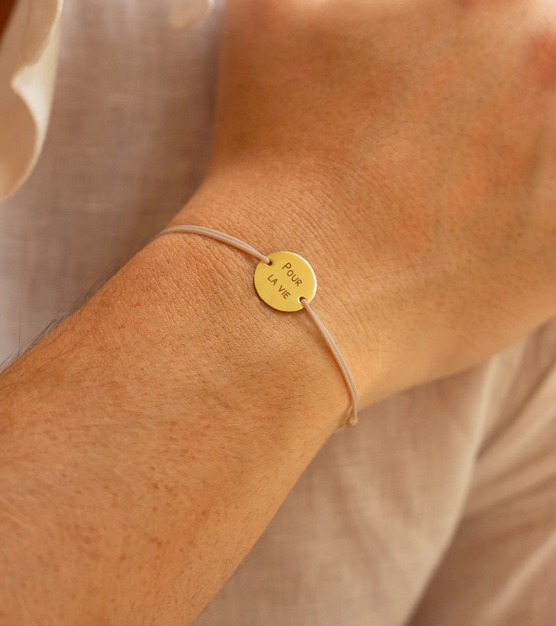 bracelet personnalisé comprenant une médaille 15mm en plaqué or, deux trous, et un cordon beige