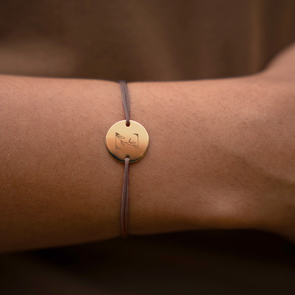 une médaille plaquée or de 15mm et de deux trous, ce bracelet personnalisé est rehaussé d'un cordon marron clair.