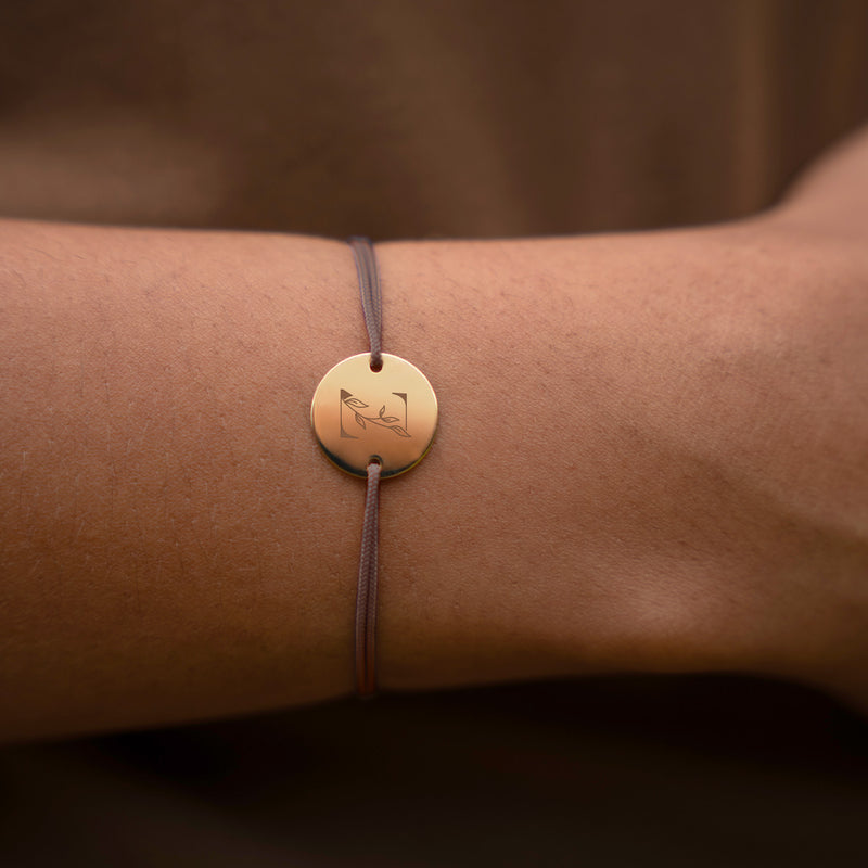 une médaille plaquée or de 15mm et de deux trous, ce bracelet personnalisé est rehaussé d'un cordon marron clair.