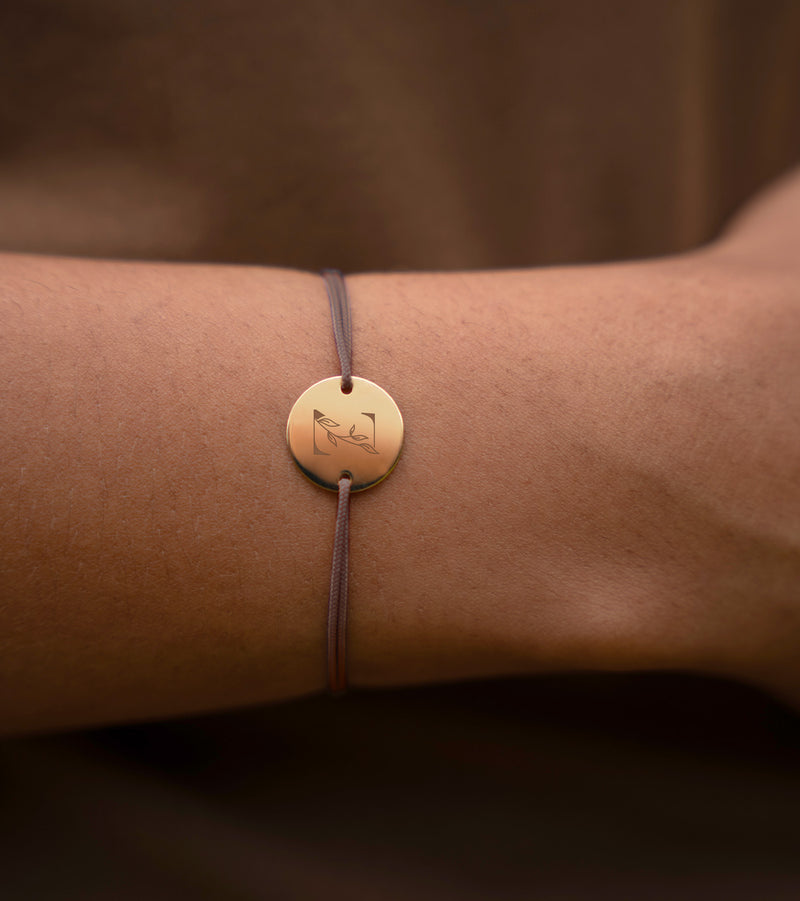 une médaille plaquée or de 15mm et de deux trous, ce bracelet personnalisé est rehaussé d'un cordon marron clair.