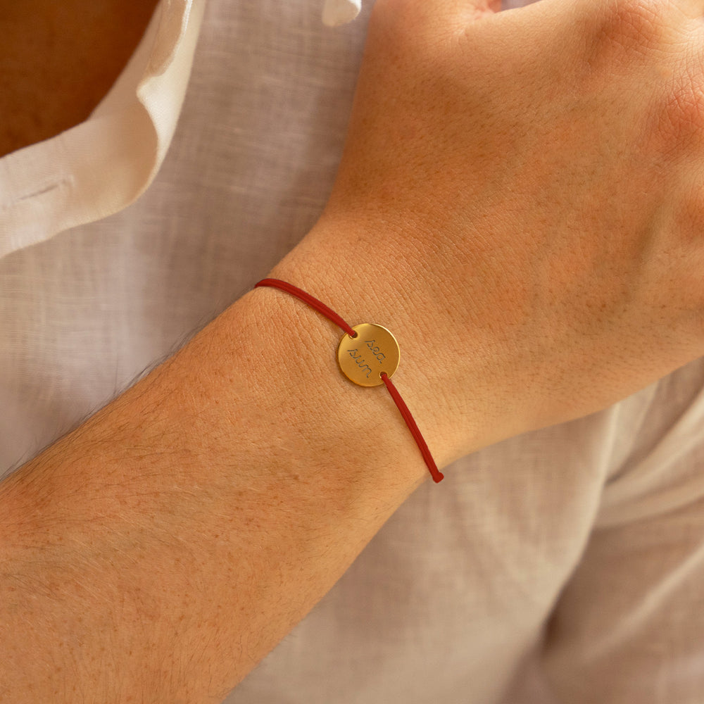  médaille plaquée or de 15mm, maintenue par deux trous, ce bracelet personnalisé se pare d'un cordon rouge.