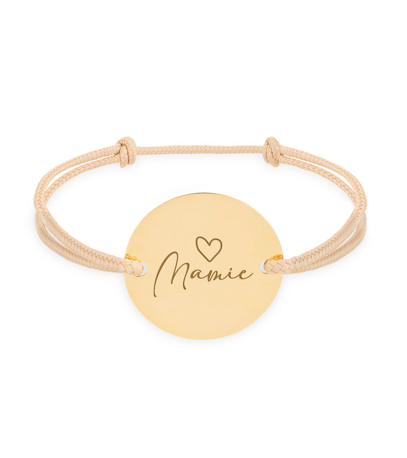 Ce bracelet personnalisé, doté d'une médaille de 20mm, de deux trous en plaqué or et d'un cordon beige, incarne l'élégance