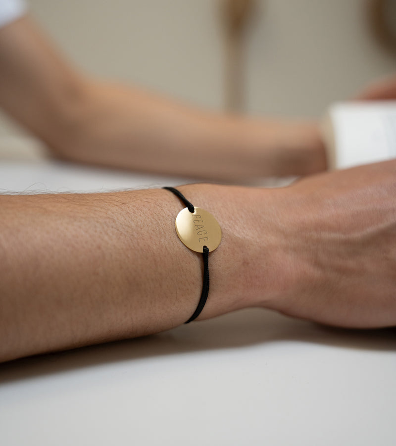 Avec une médaille personnalisée en 20mm, ce bracelet comprend deux trous en plaqué or et un cordon noir, soulignant son caractère unique.