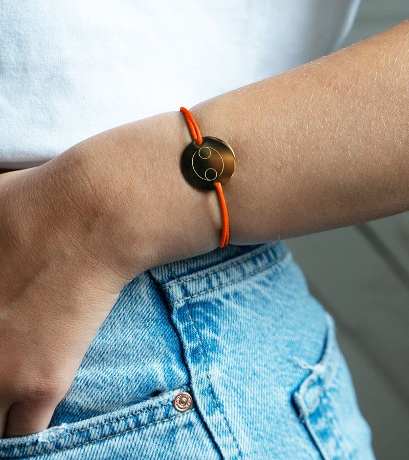 Un cordon orange fluo accompagne ce bracelet médaille, personnalisé en 20mm avec deux trous en plaqué or.
