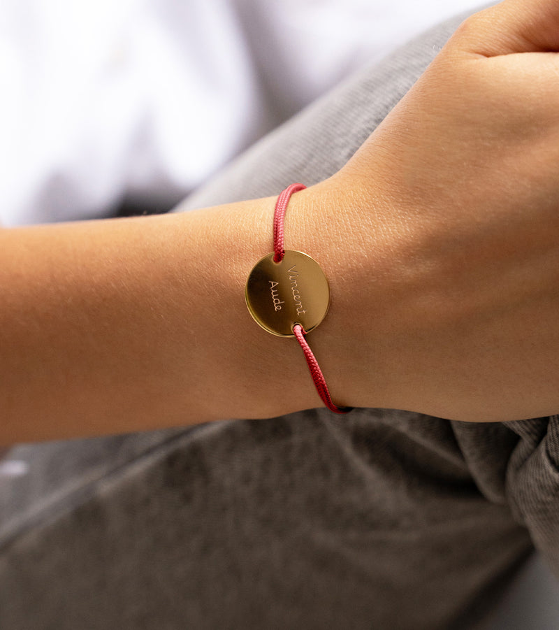 bracelet médaille en 20mm, orné de deux trous en plaqué or et agrémenté d'un cordon rouge.