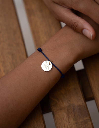 Un bracelet unique, une médaille de 15mm en plaqué or associée à un cordon bleu marine, pour un style distingué.