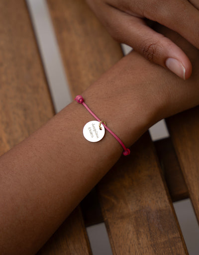 Un accessoire de mode élégant, avec une médaille de 15mm plaqué or, accompagné d'un cordon rose fuchsia.