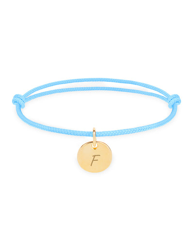 Un bracelet personnalisé en plaqué or, avec une médaille de 10mm, sur un cordon bleu pastel.