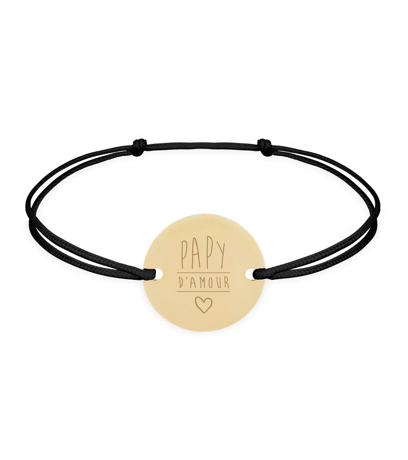 Un bracelet, orné d'une médaille de 15mm, doté de 2 trous et plaqué or. Son cordon noir ajoute une touche de sobriété