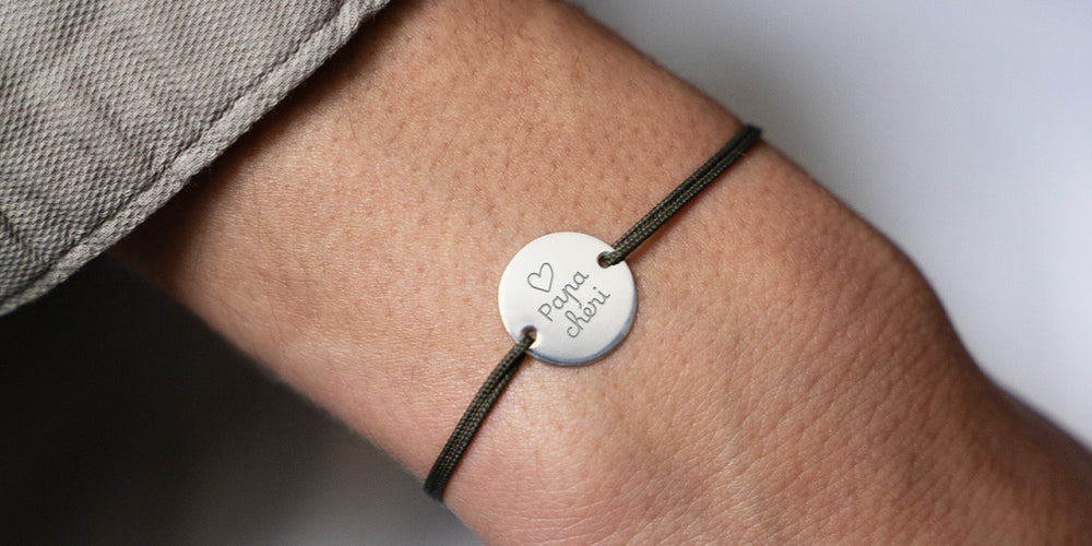 Bracelet raffiné en argent, doté d'une médaille personnalisée de 15mm et de deux trous distinctifs et accompagné d'un cordon kaki. 
