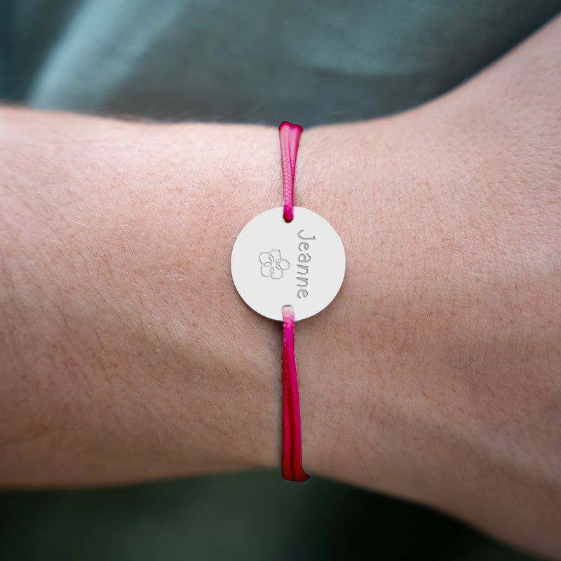 Un bracelet médaille, personnalisé en 20mm, agrémenté de deux trous en plaqué argent, ainsi qu'un cordon rose fushia.