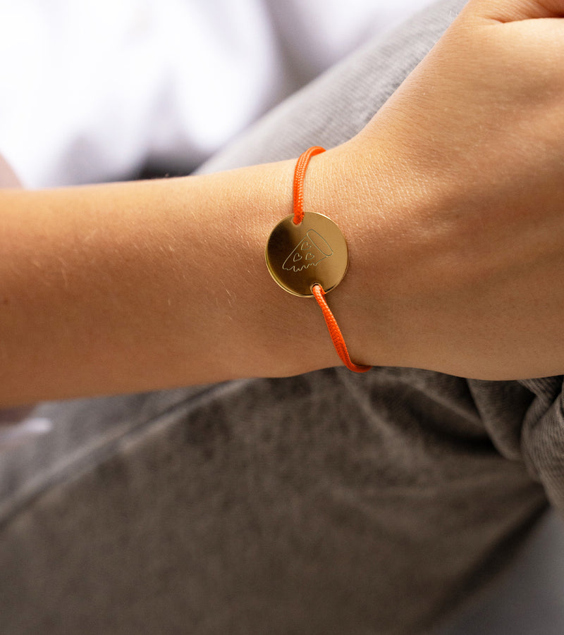 un bracelet médaille unique, personnalisé en 20mm, avec deux trous en plaqué or et un cordon orange fluo.
