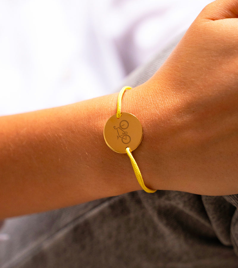 Pédalez en toute élégance ! Ce bracelet en plaqué or, orné d'un cordon jaune, est le cadeau idéal pour les cyclistes passionnés. Personnalisez-le pour un souvenir qui roule !