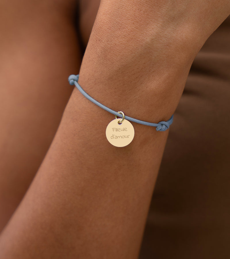 Apportez une touche d'élégance à votre tenue avec ce bracelet en cordon bleu pastel, accompagné d'une médaille plaquée or de 15mm.
