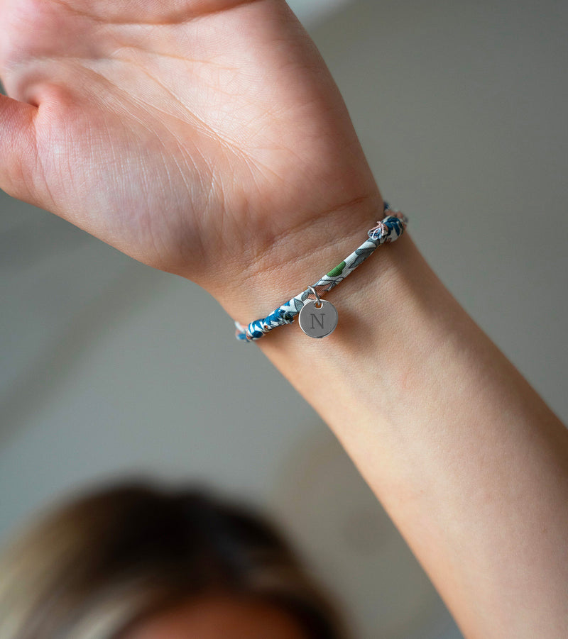 Un bracelet argenté, rehaussé d'une médaille de 10mm, enveloppée dans un ravissant Liberty Lilas.