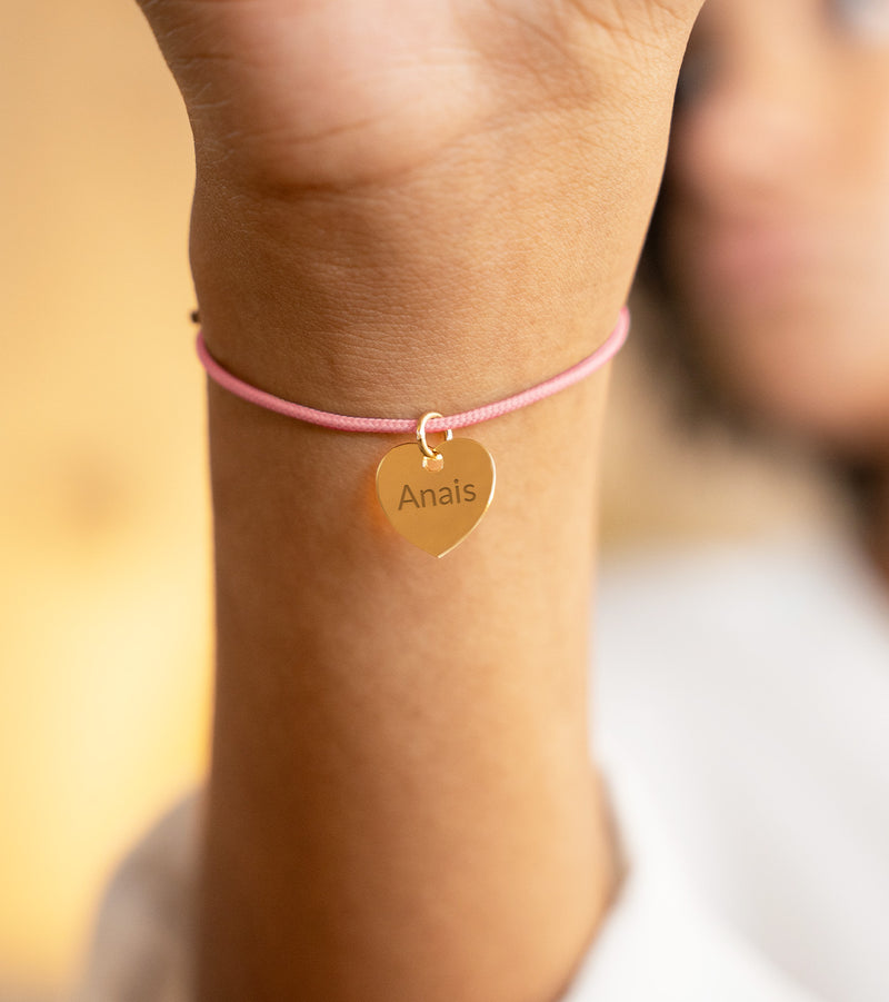 Bracelet en plaqué or avec un cœur et un cordon rose.
