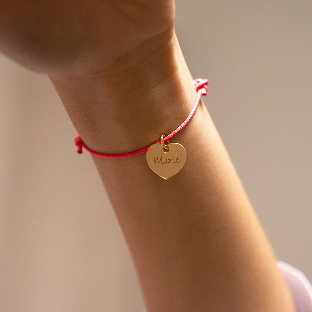 Bracelet en plaqué or, orné d'un cœur délicat de 15mm, accentué par un cordon rose fuchsia.