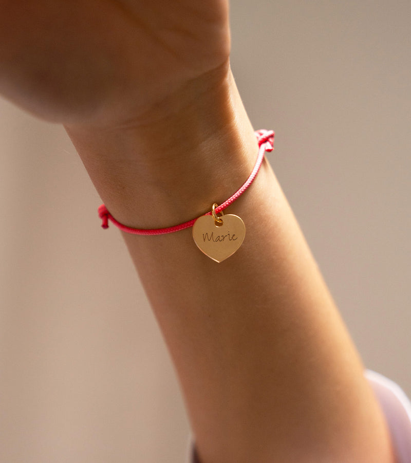 Bracelet en plaqué or, orné d'un cœur délicat de 15mm, accentué par un cordon rose fuchsia.