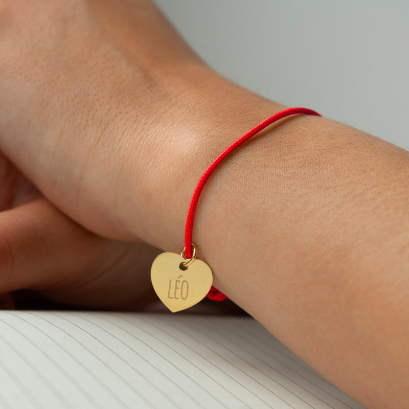 Un bracelet cordon rouge agrémenté d'un cœur plaqué or de 15mm.