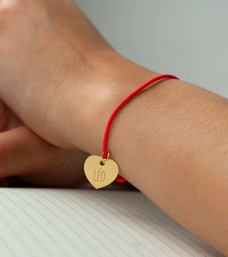 Un bracelet cordon rouge agrémenté d'un cœur plaqué or de 15mm.