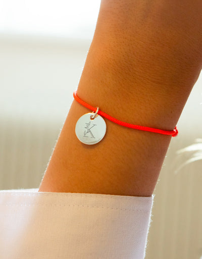 Bracelet argenté avec médaille de 15mm et cordon orange fluo. Une fusion de style moderne et de couleur vibrante.