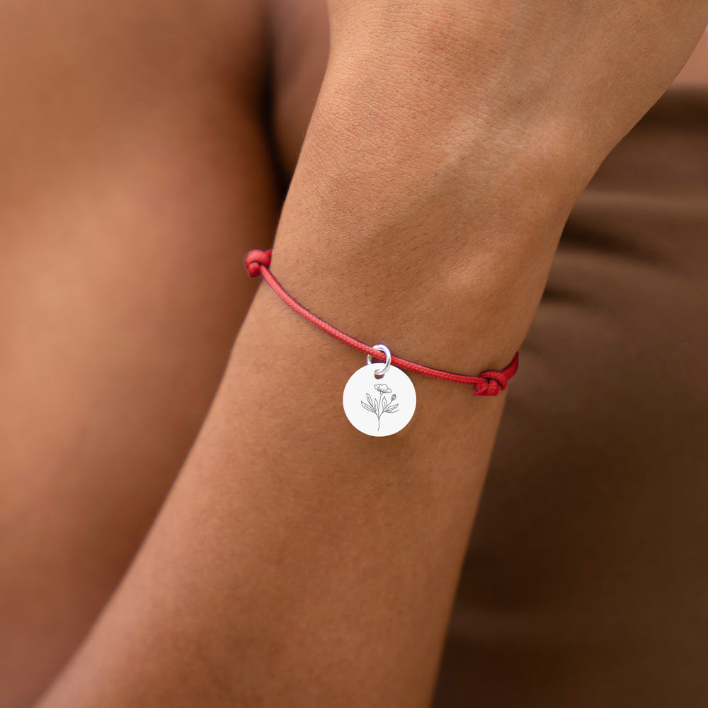Un bracelet argenté avec une médaille de 15mm sur un cordon rouge pour une touche de sophistication.