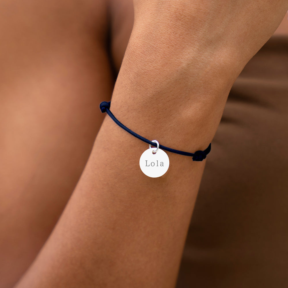 Bijou argenté avec médaille de 15mm, attaché à un cordon bleu marine.