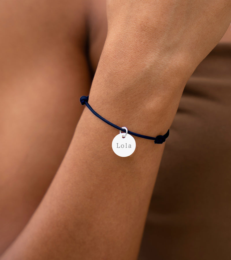 Bijou argenté avec médaille de 15mm, attaché à un cordon bleu marine.