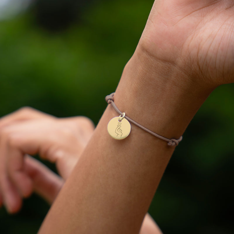Bracelet personnalisé en plaqué or avec médaille de 15mm sur cordon marron clair.