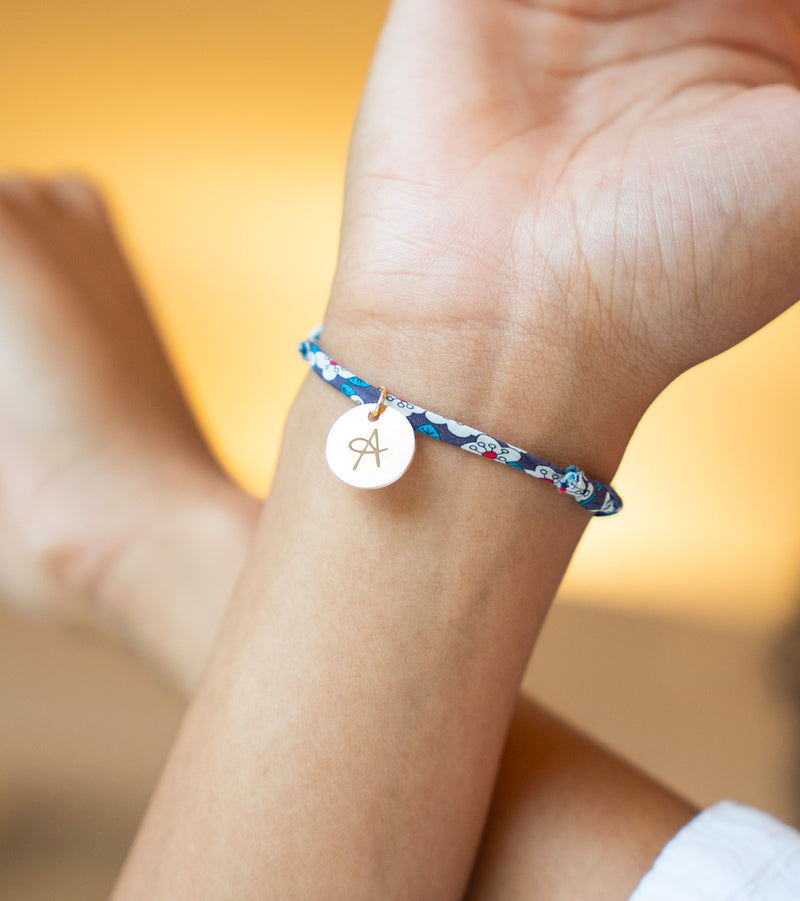 Charmant bracelet avec une médaille de 15mm en plaqué or, attachée à un lien Liberty Iris.