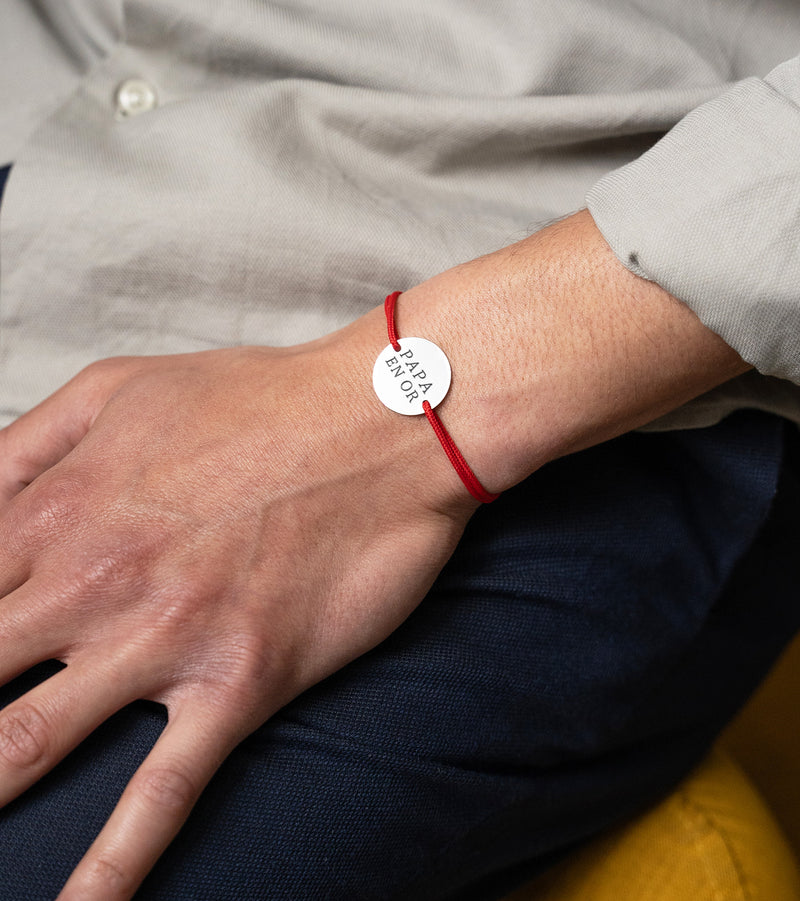 Sur cordon rouge, ce bracelet médaille en plaqué argent, personnalisé et doté de deux trous, ajoute une touche d'élégance.