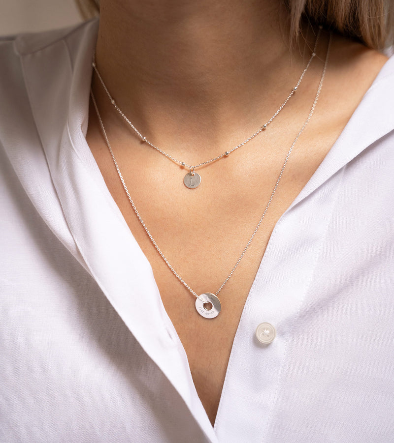 Un pendentif en forme de cible, personnalisé de 15mm en argent, assure une allure unique.