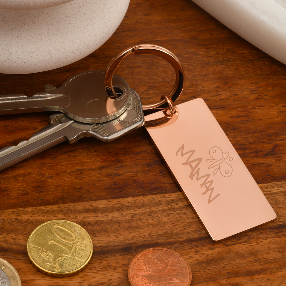 Porte-clé de forme plaque en acier inoxydable doré rose, 50 mm x 22 mm, accompagné d’un anneau rond.